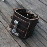 bracelet manchette viking en cuir ornée du symbole nordique du Mjolnir, le marteau de thor - photo sur fond bois - vue de dessus du bracelet
