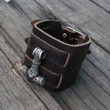 bracelet manchette viking en cuir ornée du symbole nordique du Mjolnir, le marteau de thor - photo sur fond bois - vue de dessus du bracelet