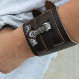 bracelet manchette viking en cuir ornée du symbole nordique du Mjolnir, le marteau de thor - photo bijou porté au bras par homme en survêtement gris sport - vue de face du bracelet