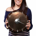 Horloge nordique murale en forme de bouclier viking - version simple -montrée par une femme tenant l'horloge des deux mains
